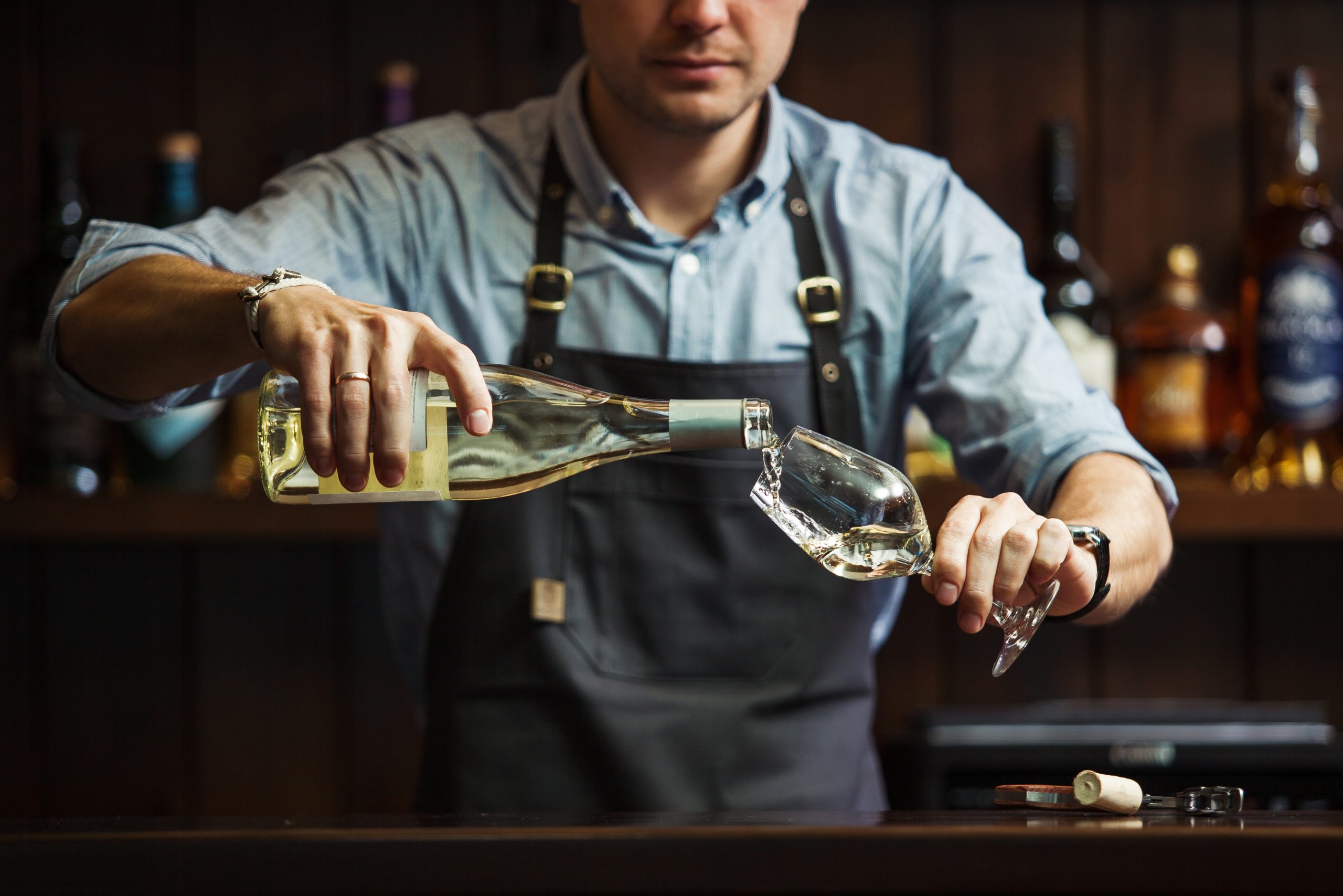 Mandlig ommelier hælder vin i t glas